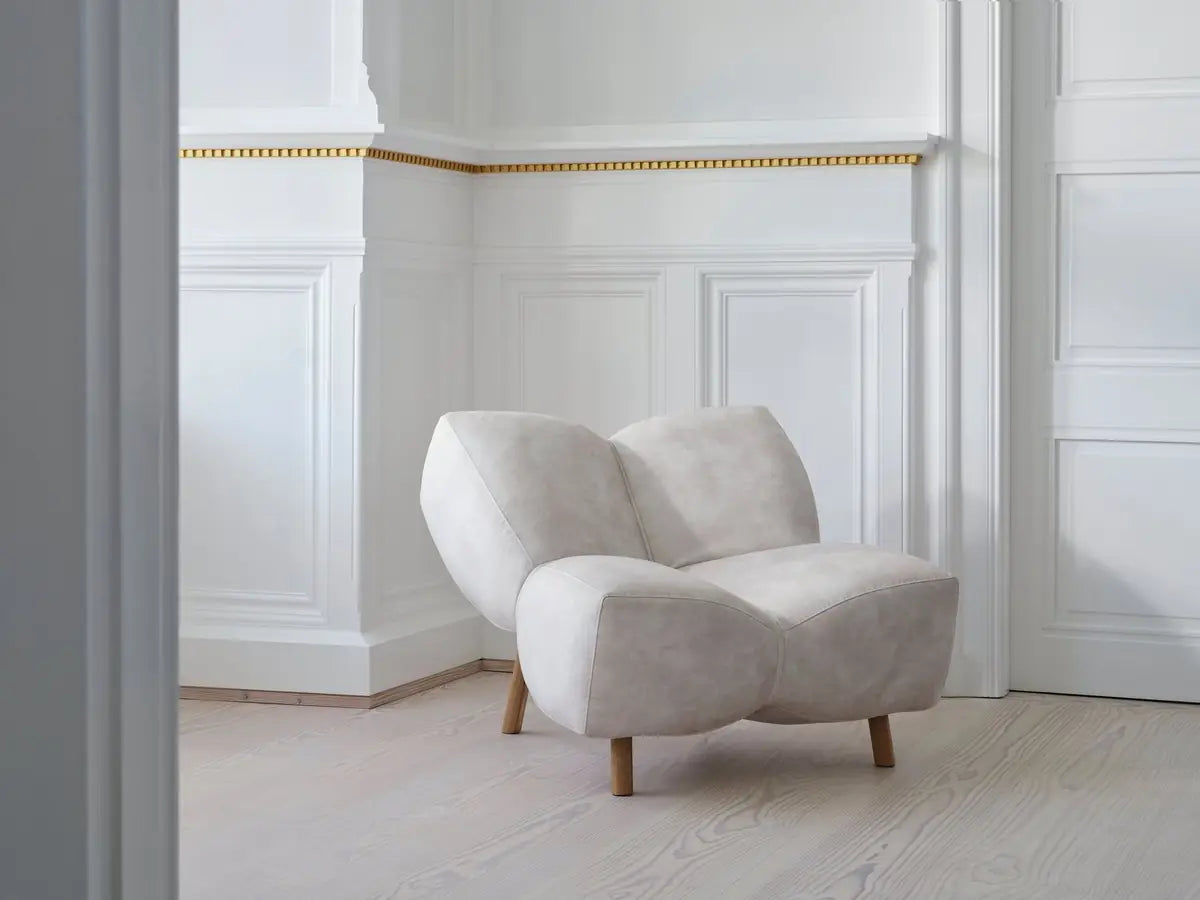 Beige armchair with wooden legs in a white-panelled room