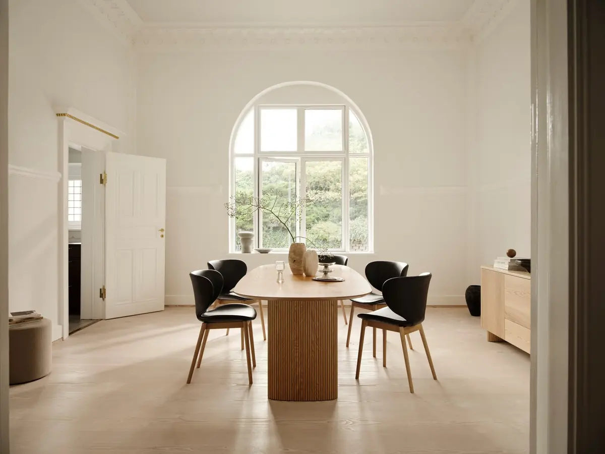 Minimalist dining room with an oval wooden table and black chairs