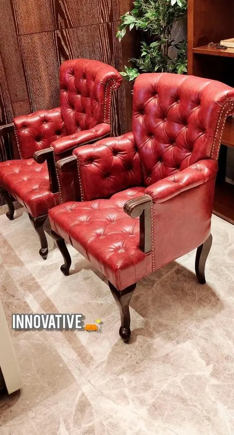Pair of red tufted leather armchairs on a marble floor
