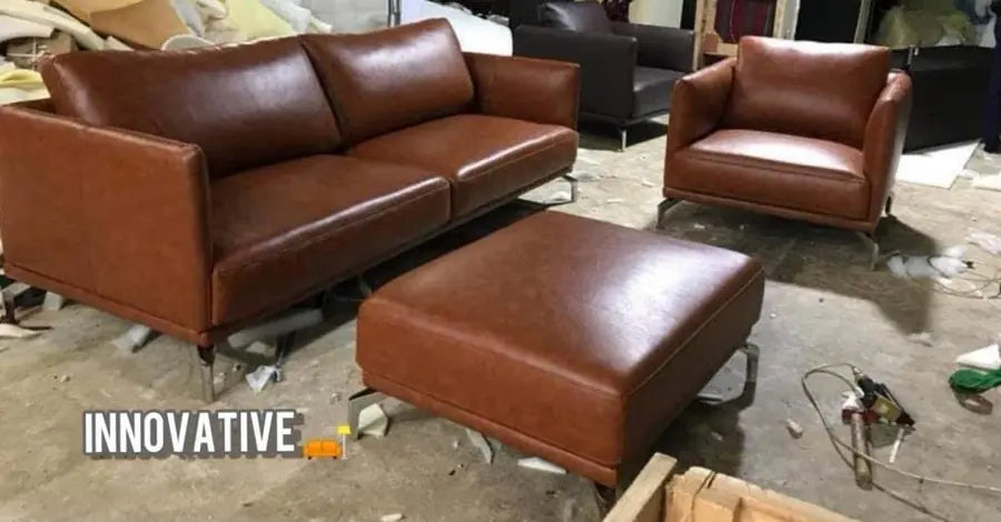 Brown leatherite three-seater sofa with armchair and ottoman on the workshop floor
