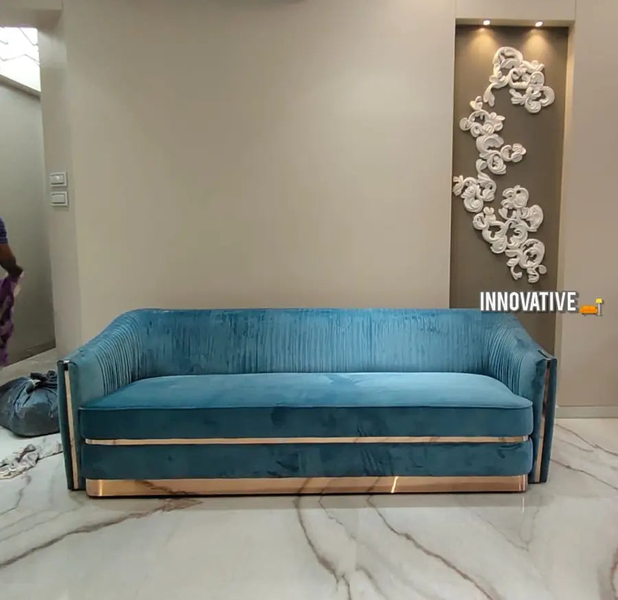 Teal pleated velvet sofa with a brass base in a bright room