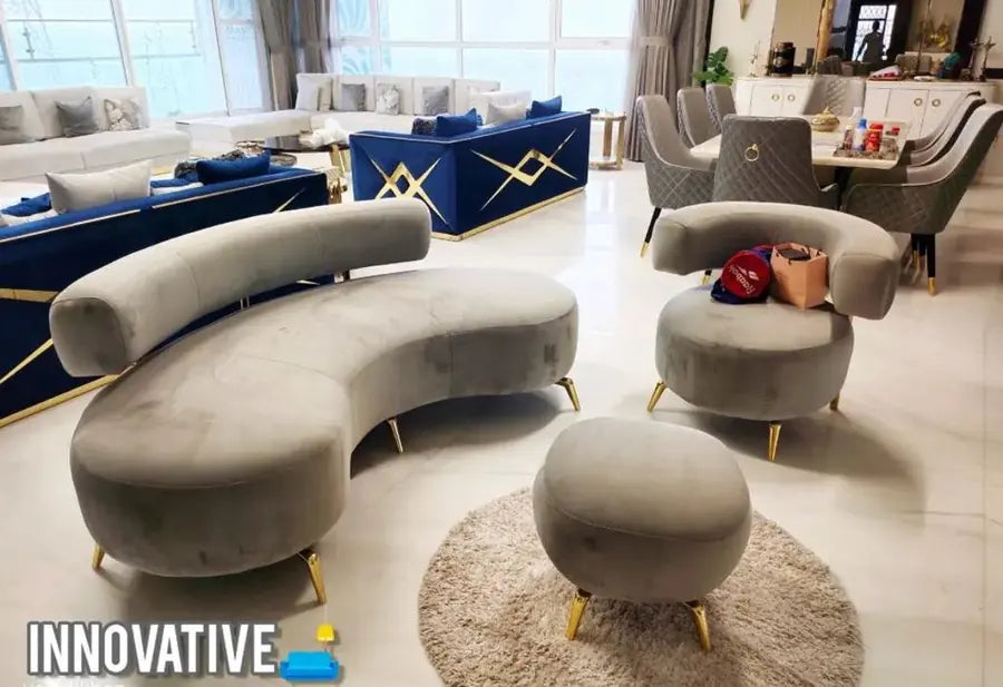 Grey curved sofa with matching accent chairs and a pouf on a round rug