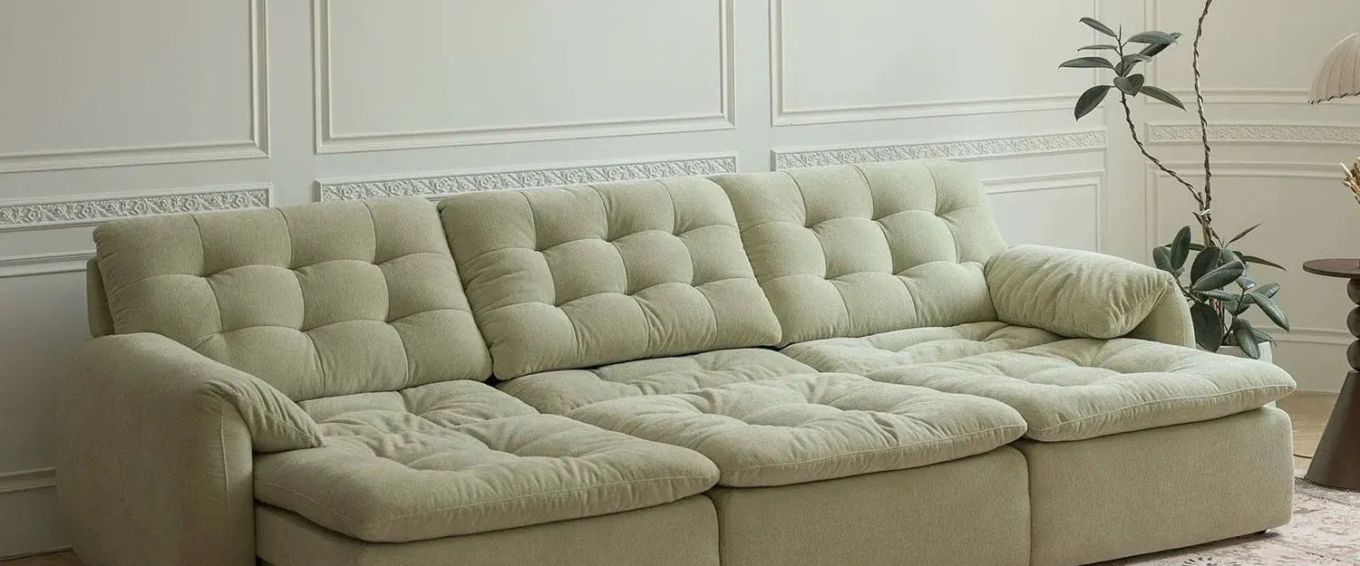 Sage green extendable sofa with its seat pulled out, shown with people reading and a built-in cup-holder tray